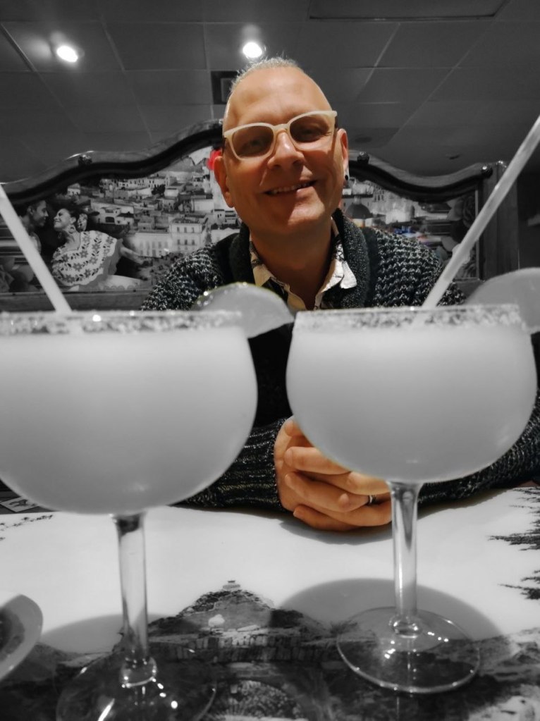 spouse behind two large margaritas in restaurant