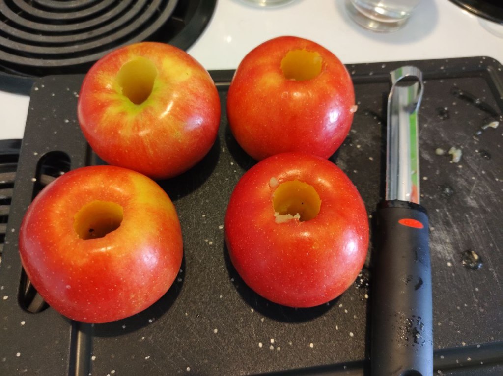 four cored apples beside coring tool