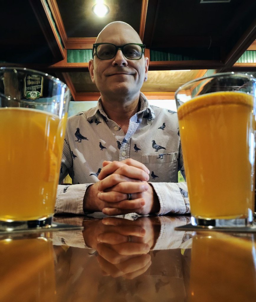 Spouse posing with two draft beers in pub.